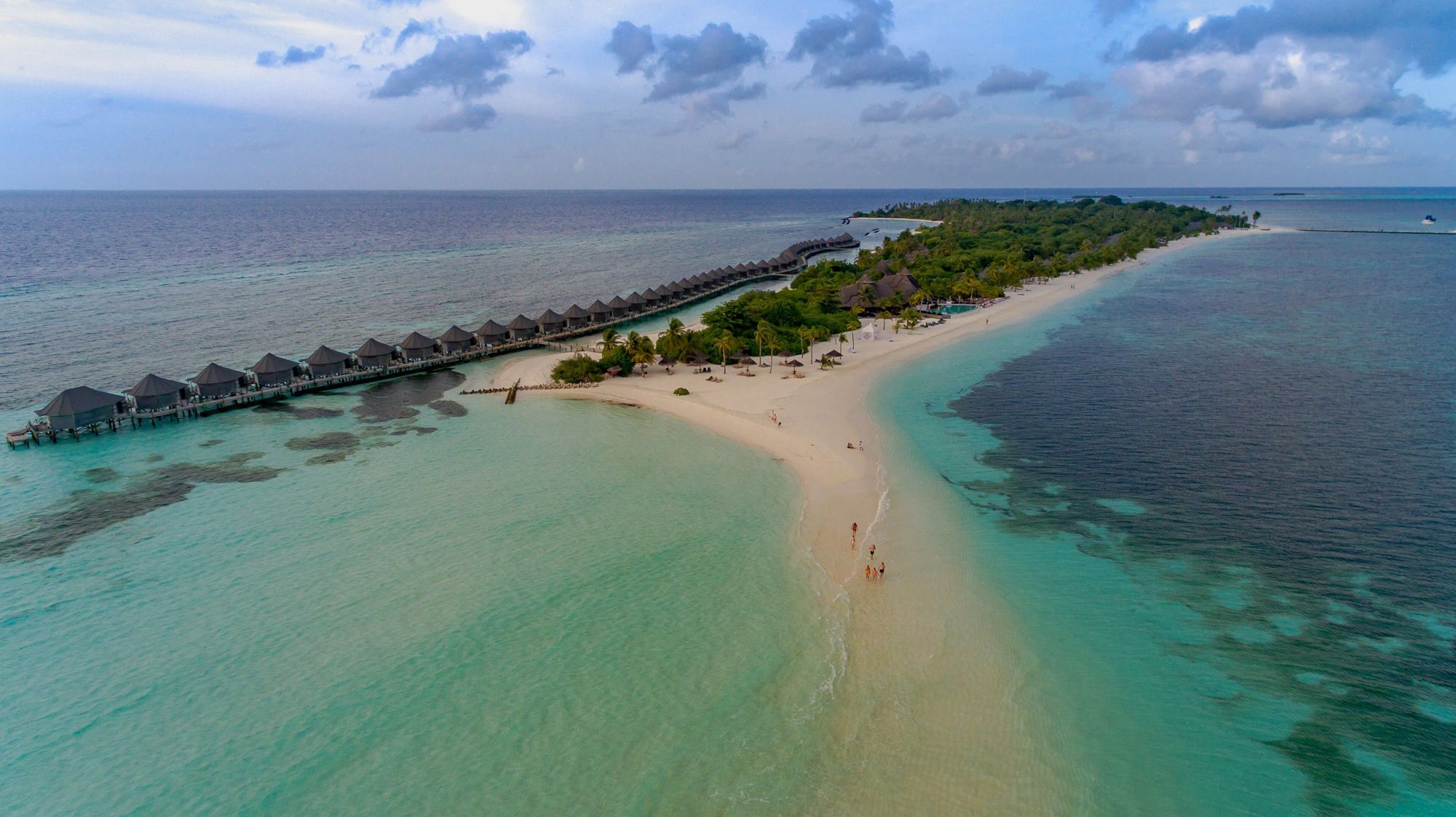 Aerial view of a white sandbank curving through a turquoise Maldives lagoon